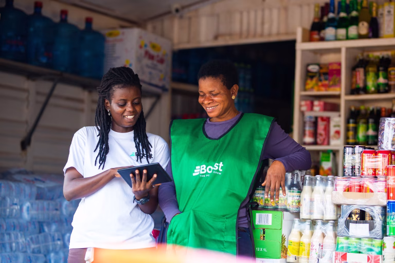 Two women smile while looking at tablet